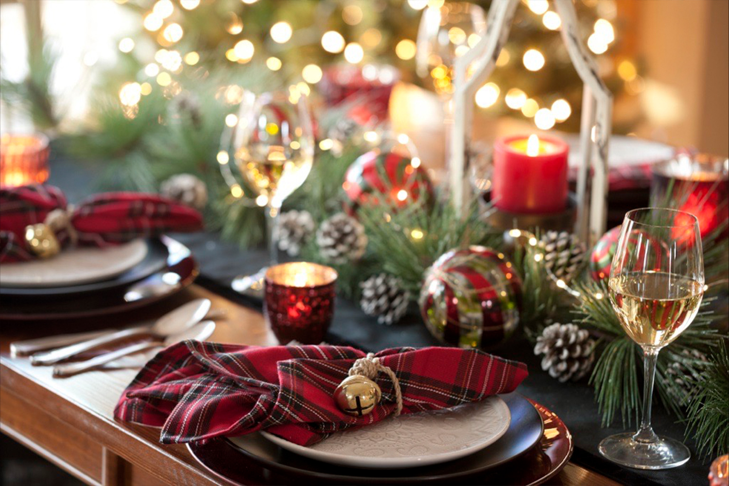 Christmas dining setup with glasses, napkins and bright lights. 